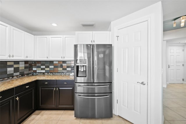 kitchen featuring visible vents, white cabinets, stainless steel fridge, and backsplash