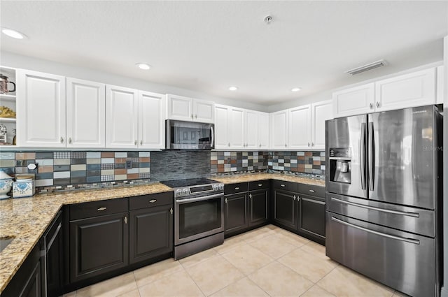 kitchen with stainless steel appliances, visible vents, white cabinets, dark cabinetry, and tasteful backsplash