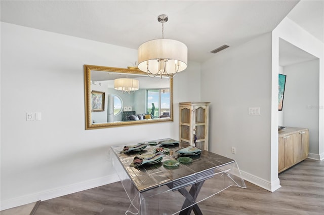 dining room with wood finished floors, visible vents, baseboards, and an inviting chandelier