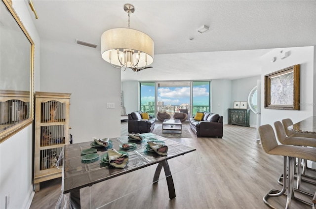 dining space featuring a chandelier, expansive windows, visible vents, and wood finished floors