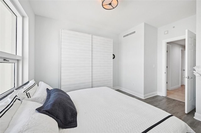 bedroom with visible vents, baseboards, and wood finished floors