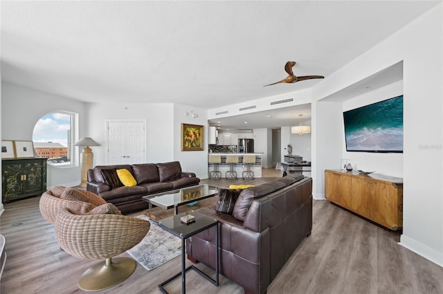 living area featuring visible vents, baseboards, and wood finished floors