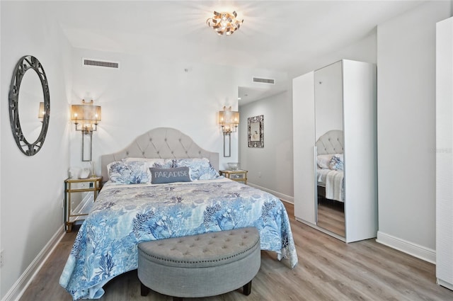 bedroom featuring light wood finished floors, baseboards, and visible vents