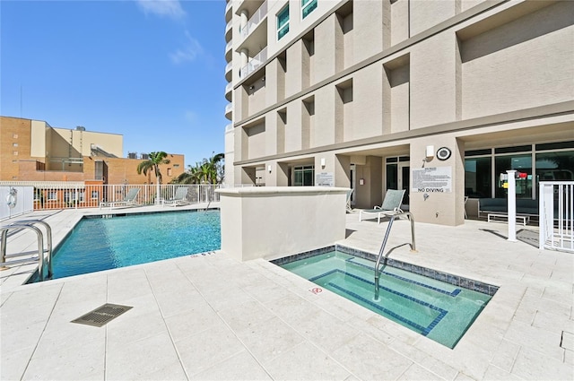 community pool featuring a community hot tub, a patio area, and fence