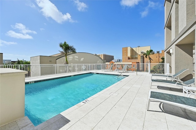 community pool with a patio area and fence