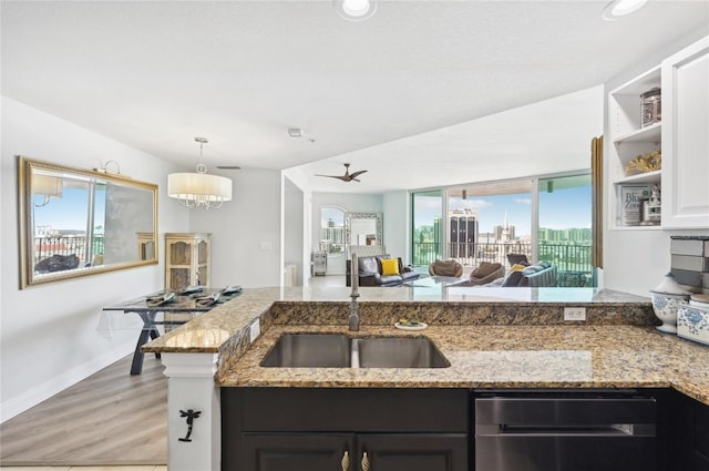 kitchen featuring light wood-style flooring, a city view, a sink, open floor plan, and light stone countertops