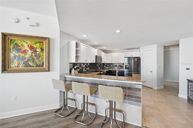 kitchen featuring open shelves, decorative backsplash, appliances with stainless steel finishes, white cabinetry, and a peninsula