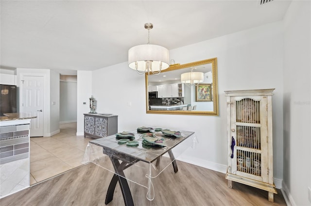 dining room with a chandelier, light tile patterned flooring, and baseboards