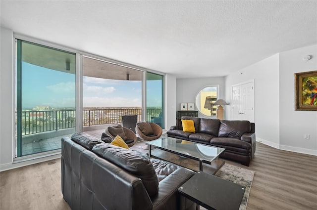 living area featuring baseboards, a textured ceiling, floor to ceiling windows, and wood finished floors