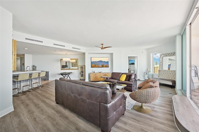 living area featuring light wood-type flooring, visible vents, and a ceiling fan