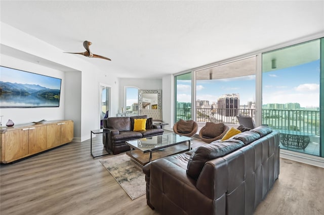 living area featuring light wood-style floors, ceiling fan, a view of city, and baseboards