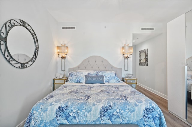 bedroom featuring baseboards, visible vents, and wood finished floors