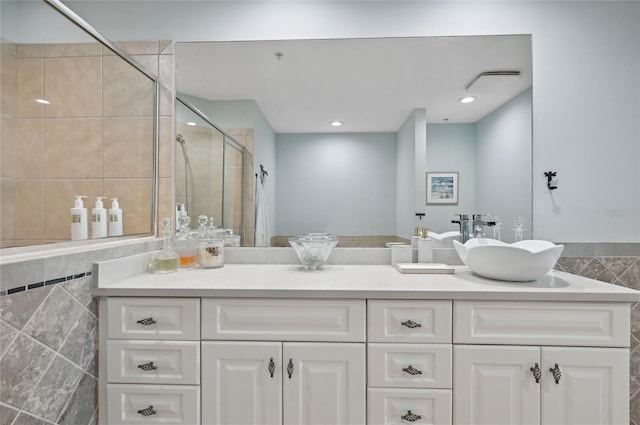 full bath with double vanity, a stall shower, a sink, tile walls, and recessed lighting