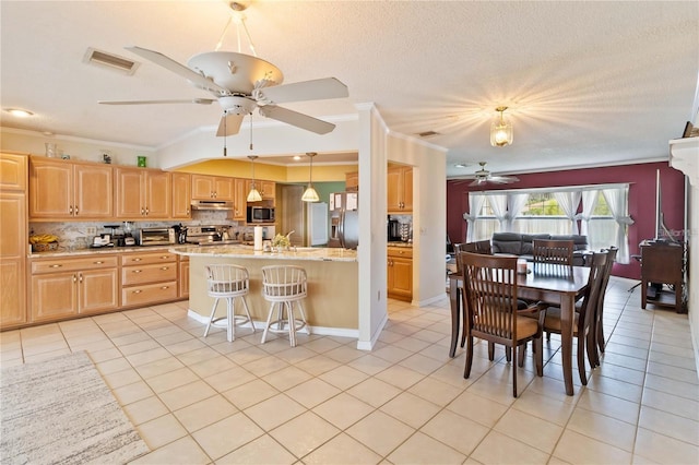 kitchen with stainless steel appliances, light tile patterned flooring, ornamental molding, and pendant lighting