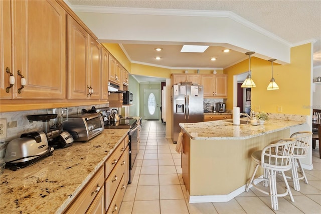 kitchen with light stone counters, a skylight, hanging light fixtures, appliances with stainless steel finishes, and a kitchen breakfast bar