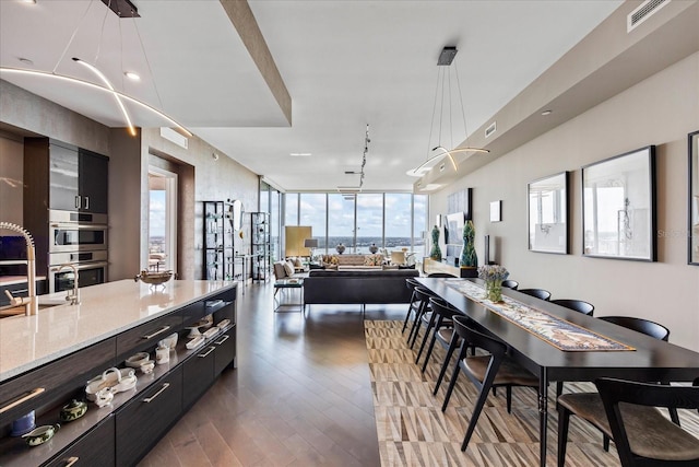 kitchen featuring decorative light fixtures, track lighting, stainless steel double oven, light stone countertops, and hardwood / wood-style floors