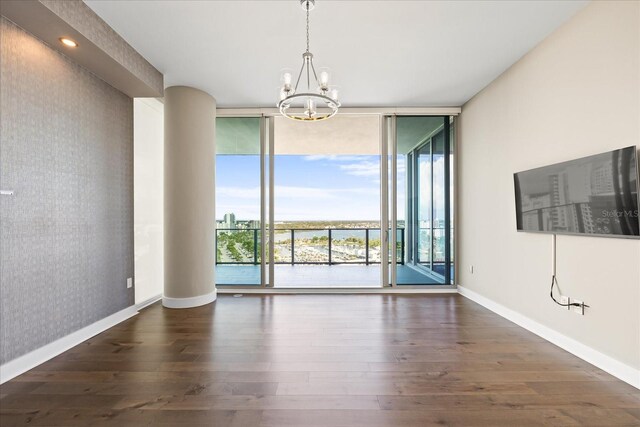 1155 N Gulfstream Ave Unit 1709, Sarasota, FL 34236 - spare room featuring a chandelier, expansive windows, wood finished floors, and wallpapered walls