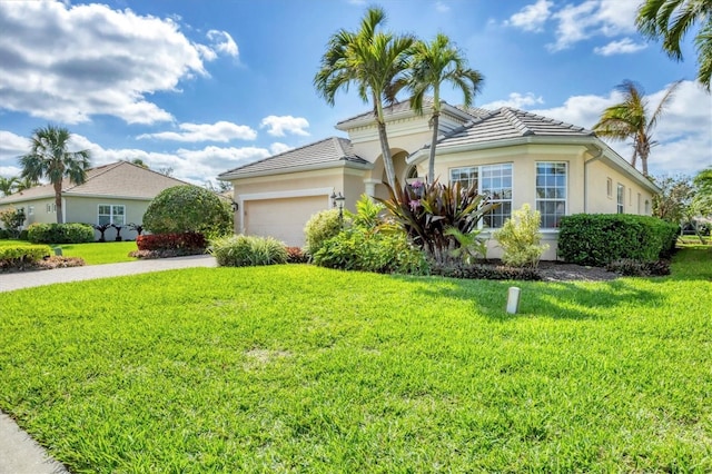 view of front of property featuring driveway, a tiled roof, an attached garage, a front lawn, and stucco siding