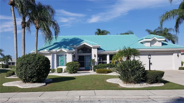 single story home with a garage, a tile roof, concrete driveway, stucco siding, and a front yard