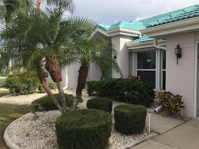 view of side of home featuring a tile roof and stucco siding