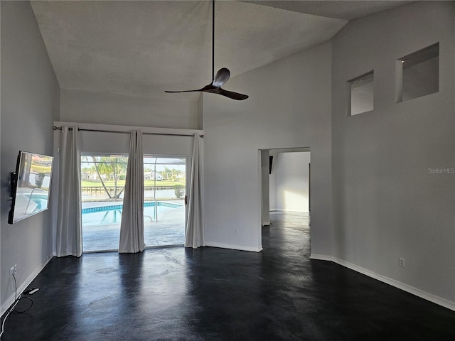 empty room with high vaulted ceiling, finished concrete floors, baseboards, and a ceiling fan