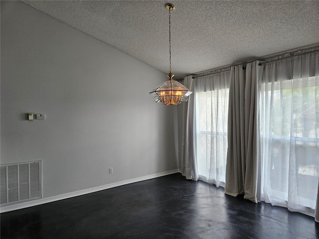 spare room featuring a textured ceiling, visible vents, and baseboards