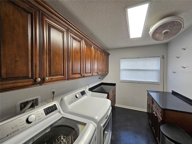 washroom with a textured ceiling, a sink, baseboards, washer and dryer, and cabinet space