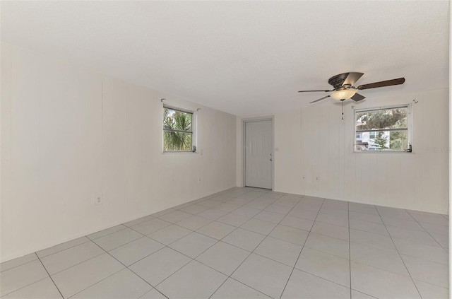 empty room with a textured ceiling, ceiling fan, and light tile patterned floors