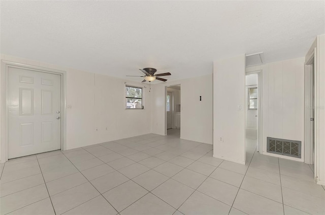 empty room with ceiling fan, light tile patterned flooring, and a textured ceiling