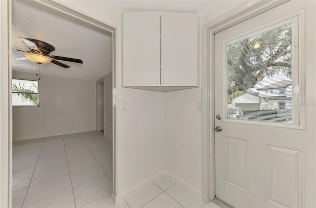 doorway featuring light tile patterned flooring, ceiling fan, and a textured ceiling