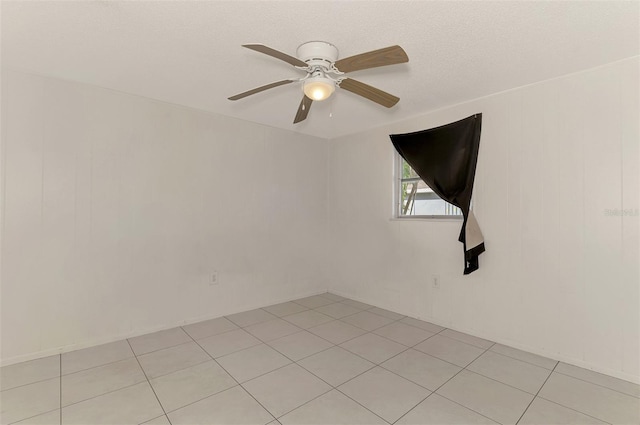 empty room with light tile patterned floors, ceiling fan, and a textured ceiling