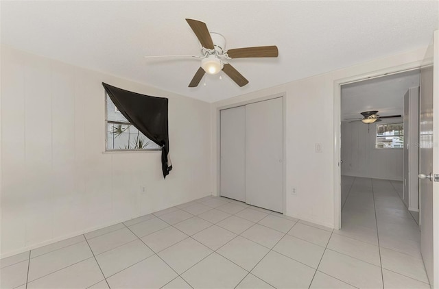 unfurnished bedroom featuring ceiling fan, light tile patterned flooring, and a closet