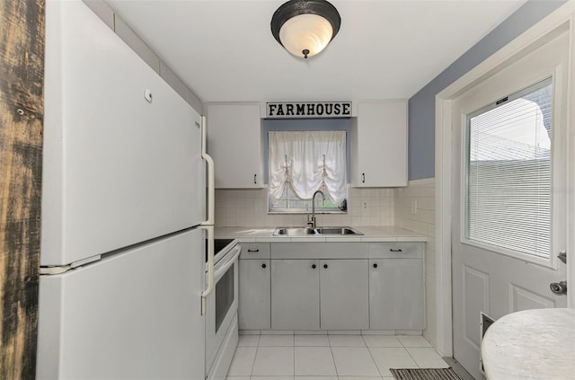 kitchen with sink, white appliances, tasteful backsplash, and light tile patterned floors