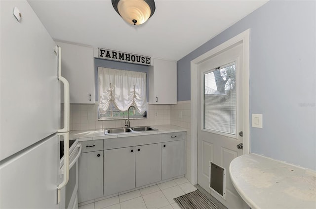 kitchen with light tile patterned flooring, sink, white appliances, and tasteful backsplash