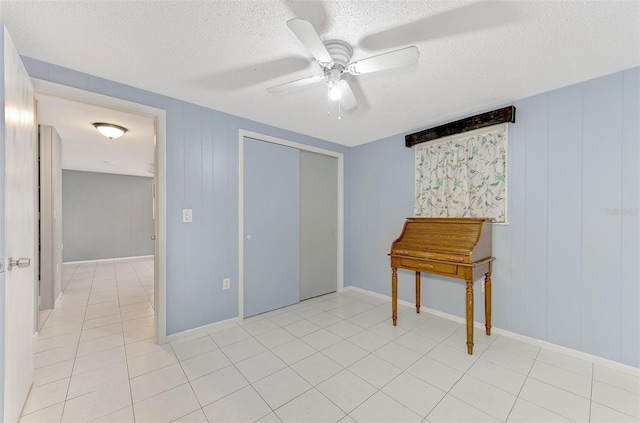 unfurnished bedroom with light tile patterned floors, ceiling fan, a closet, and a textured ceiling