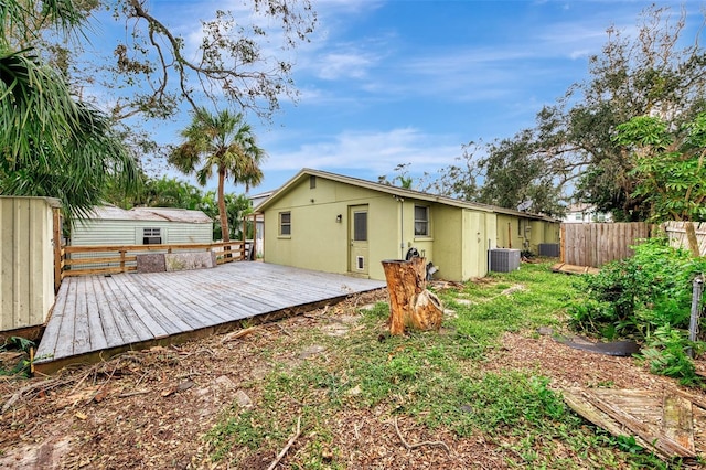 rear view of house featuring a deck, central AC, and a storage shed