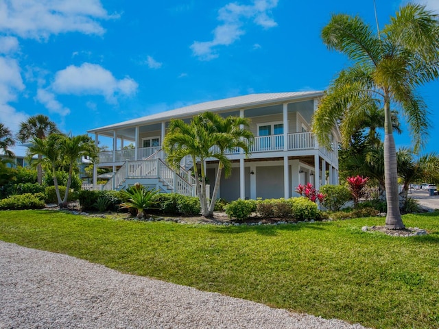 coastal home featuring a porch, a front lawn, and stairs