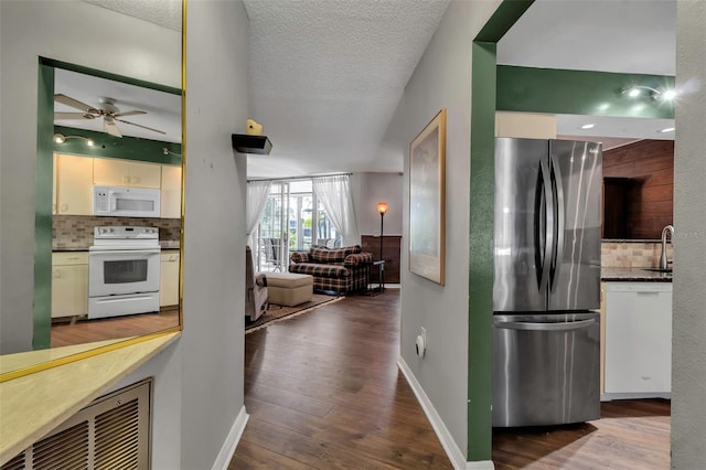 kitchen with white appliances, wood-type flooring, a textured ceiling, and backsplash