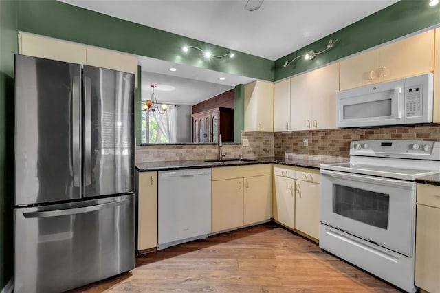 kitchen featuring sink, tasteful backsplash, light wood-type flooring, white appliances, and cream cabinets