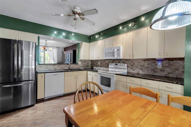 kitchen with sink, hanging light fixtures, white appliances, ceiling fan with notable chandelier, and decorative backsplash