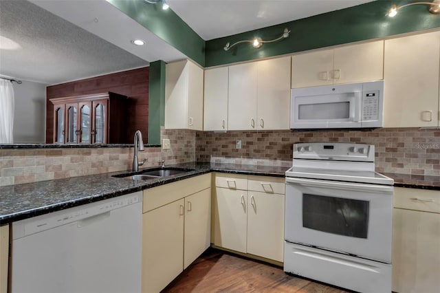 kitchen with sink, white appliances, dark stone counters, cream cabinets, and backsplash