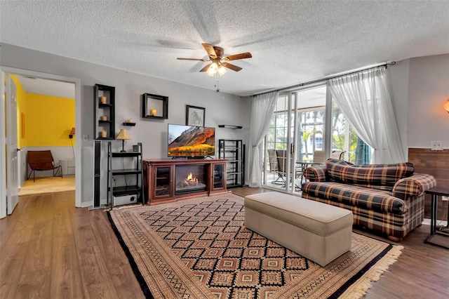 living room featuring hardwood / wood-style flooring, ceiling fan, and a textured ceiling