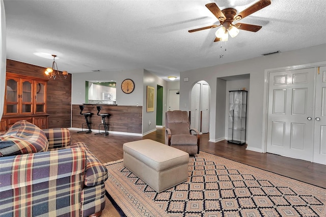 living room featuring wood-type flooring, ceiling fan, a textured ceiling, and wood walls