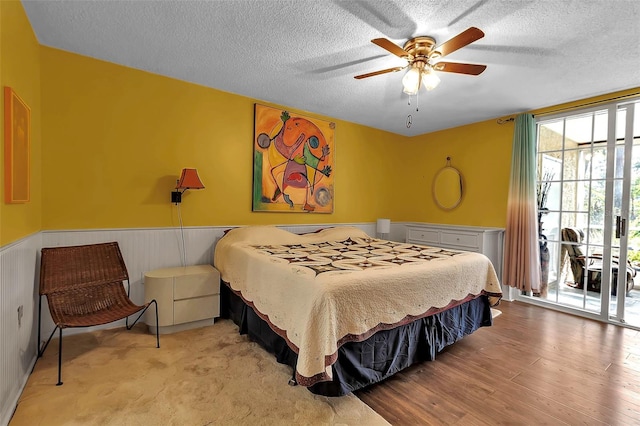 bedroom featuring ceiling fan, access to exterior, a textured ceiling, and light hardwood / wood-style floors