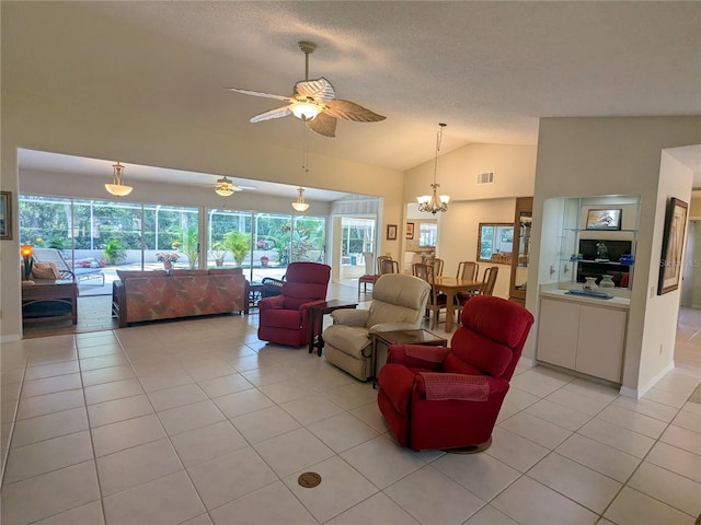 tiled living room featuring ceiling fan with notable chandelier, a healthy amount of sunlight, lofted ceiling, and a textured ceiling