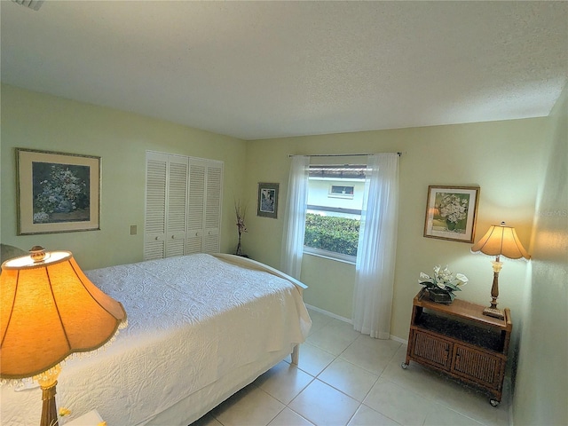 bedroom featuring light tile patterned floors, a closet, and a textured ceiling