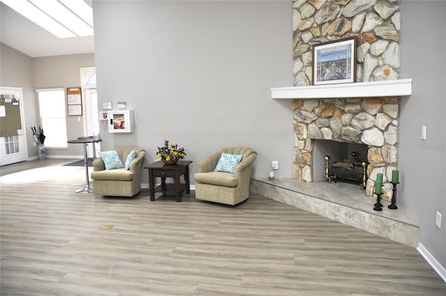 sitting room with a fireplace, lofted ceiling, and light wood-type flooring