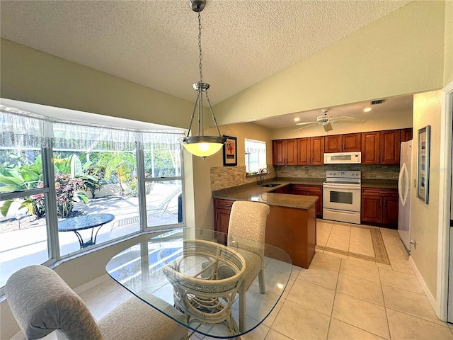 dining space with sink, vaulted ceiling, ceiling fan, light tile patterned floors, and a textured ceiling