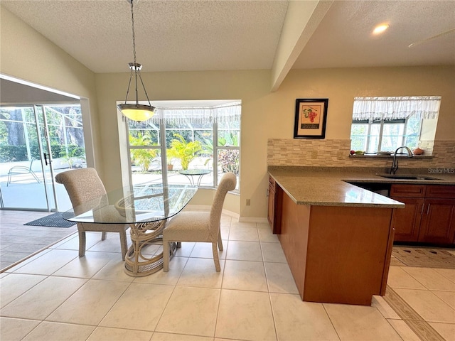 tiled dining room featuring sink, a textured ceiling, and a healthy amount of sunlight