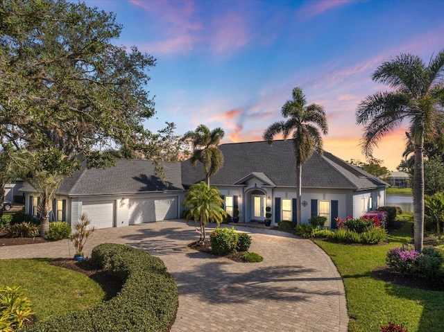 ranch-style home featuring a garage and a lawn